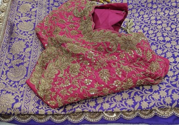 Pink blouse with maggam work embroidery on it and a saree which has embroidered scallop border kept on the table