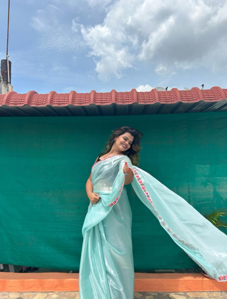 A model wearing sky blue Jimmy choo saree with floral thread embroidery border with black velvet sleeveless blouse