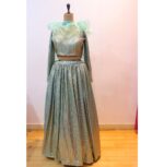 Mint green designer lehenga in shimmering Lycra fabric, paired with a full-sleeve blouse and an organza dupatta with ruffle detailing, perfect for weddings, receptions, and festive occasions.