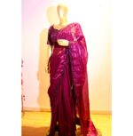 "Royal wine Jimmy Choo silk saree adorned with shimmering stones and delicate hanging lace detailing, paired with a matching raw silk blouse for a regal look."